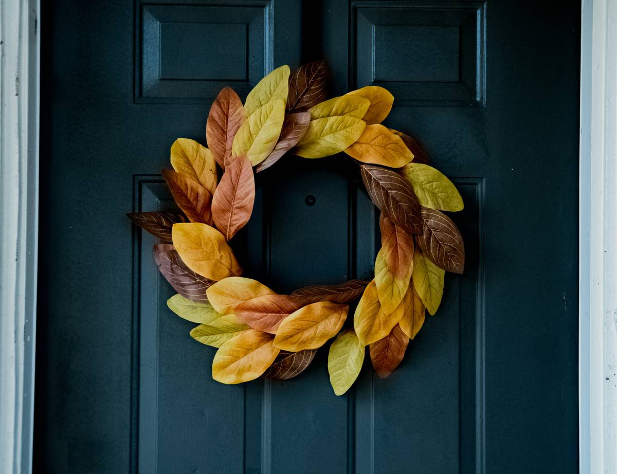 thanksgiving themed door decorations featuring a rustic wreath with faux pumpkins and burlap ribbon on a wooden front door