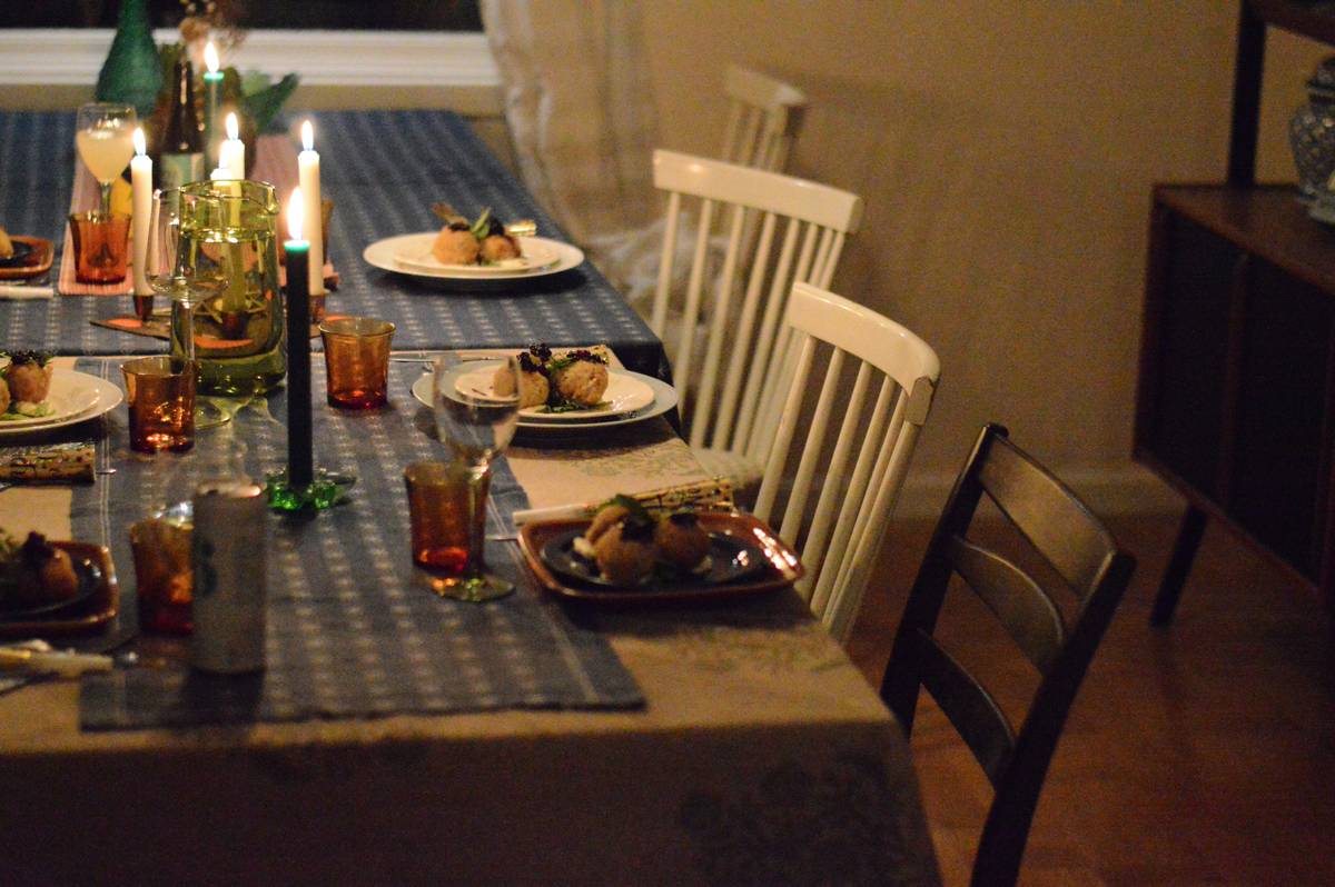 thanksgiving decor for home featuring a rustic wooden table with eucalyptus, white pumpkins, and amber candles