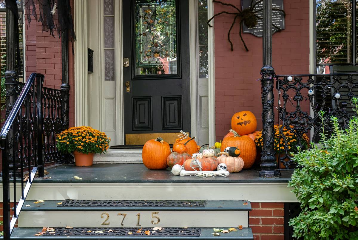 thanksgiving home outdoor decor featuring hay bales, gourds, and lanterns on a covered porch